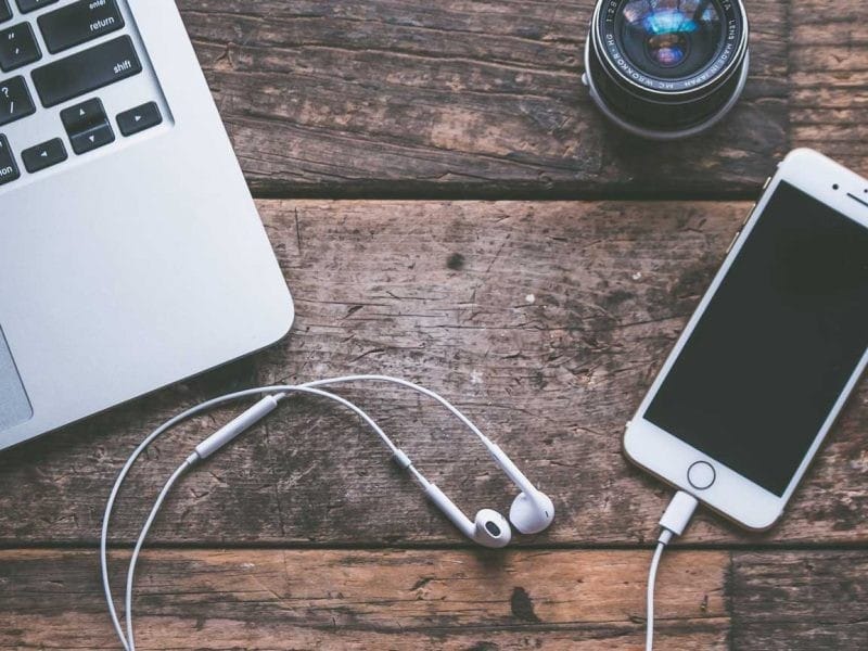 imagen cenital de mesa con laptop y móvil con auriculares para escuchar una prueba de nivel de inglés b2